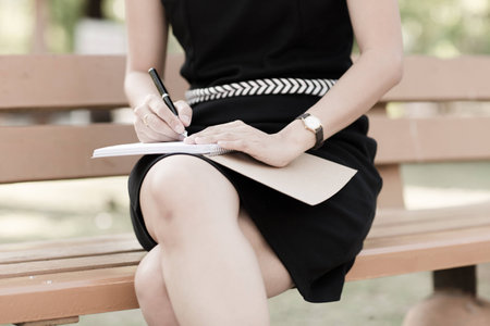 Young business woman planing, writing and reviewing report at city park.の写真素材