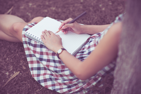 Close-up of a young girl writing into her diary, in the parkの写真素材