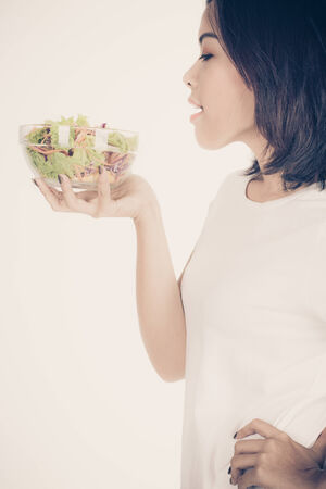 Portrait of a fit healthy hispanic woman eating a fresh salad isolated on whiteの写真素材