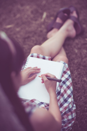 Close-up of a young girl writing into her diary, in the parkの写真素材