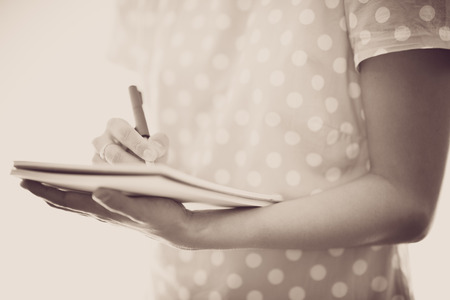 Young female is writing notes and planning her scheduleの写真素材