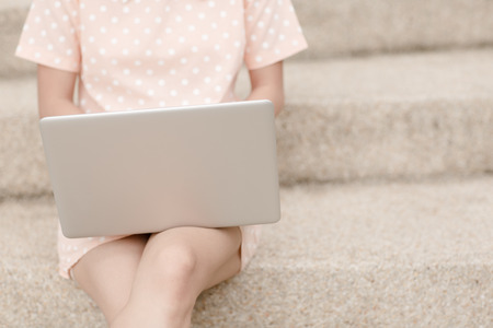 Young woman using laptop on steps outdoorsの写真素材