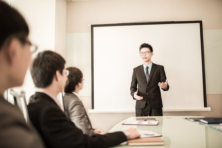 Smiling businessman discussing plans with his colleagues in board meeting.asianの写真素材