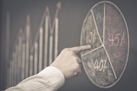 Side view of a businessman's hand. Business graph on a blackboard.の写真素材