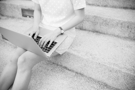 Young woman using laptop on steps outdoorsの写真素材