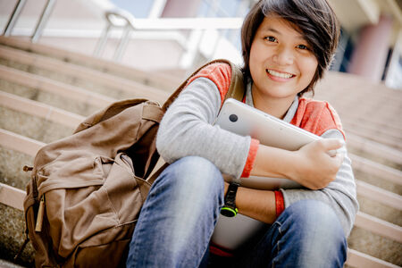 attractive female college student sitting on stairsの写真素材