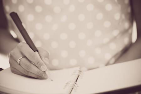 Young female is writing notes and planning her scheduleの写真素材