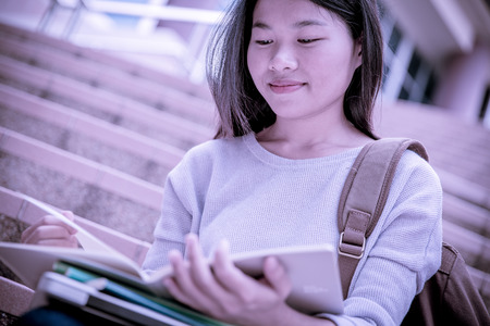 attractive female college student sitting on stairsの写真素材