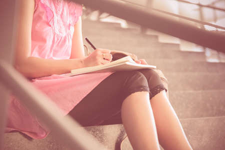 attractive female college student sitting on stairsの写真素材