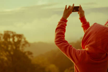 woman hiker taking photo with smart phone at mountain peakの写真素材