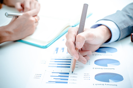 Business people discussing the charts and graphs showing the results of their successful teamworkの写真素材