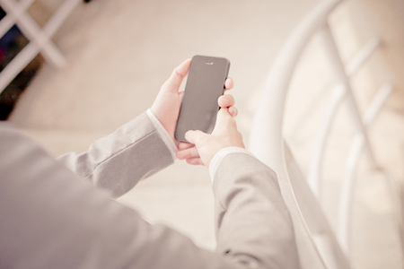 Young businessman using a phone sitting on the stairsの写真素材