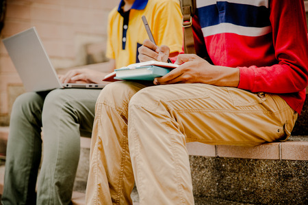 young college student reading book on stairsの写真素材