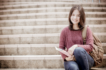 attractive female college student sitting on stairsの写真素材