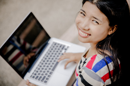 Young woman using laptop on steps outdoorsの写真素材