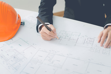 Closeup cropped image of a young male architect working on blueprints spread out on a tableの写真素材