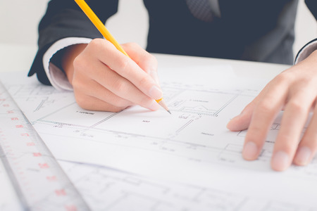 Hands of civil engineer correcting a blueprint