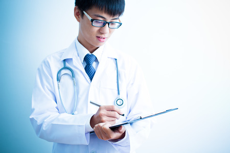 Close-up Of Male Doctor Filling The Medical Formの写真素材