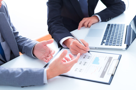 Business people discussing the charts and graphs showing the results of their successful teamworkの写真素材