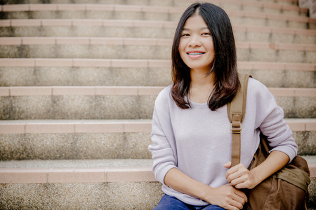attractive female college student sitting on stairsの写真素材
