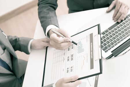 Two businessmen looking at report and having a discussion in office.の写真素材