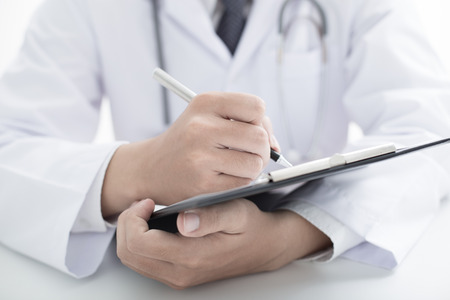 Close-up Of Male Doctor Filling The Medical Formの写真素材
