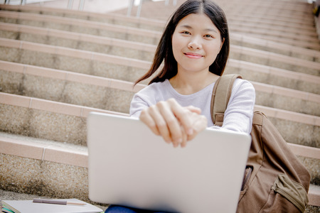 Young woman using laptop on steps outdoorsの写真素材