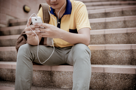 students sitting on stairs with their smartphonesの写真素材