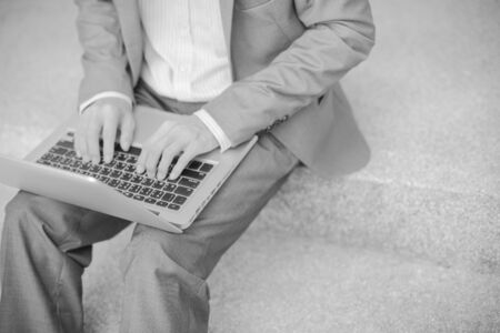 Businessman using laptop pc. He is sitting on a stairs.の写真素材