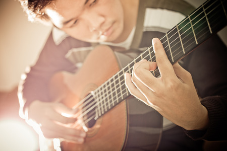 Practicing in playing guitar. Handsome young men playing guitarの写真素材