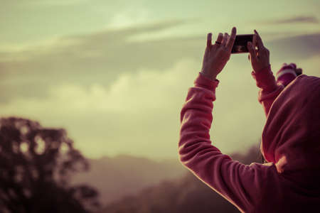 woman hiker taking photo with smart phone at mountain peakの写真素材