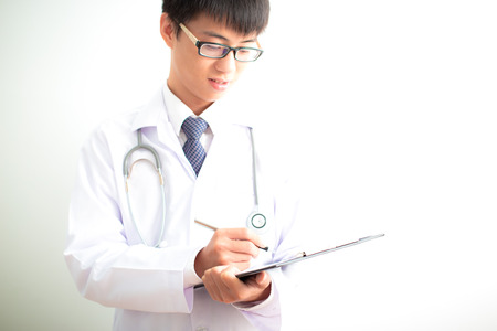 Close-up Of Male Doctor Filling The Medical Formの写真素材