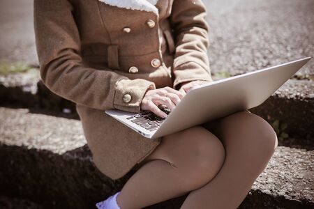 Young woman using laptop on steps outdoorsの写真素材