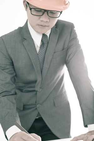 Closeup cropped image of a young male architect working on blueprints spread out on a tableの写真素材