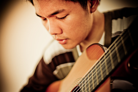 Practicing in playing guitar. Handsome young men playing guitarの写真素材