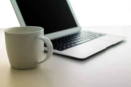 Cappuccino cup on laptop. Isolated on white backgroundの写真素材