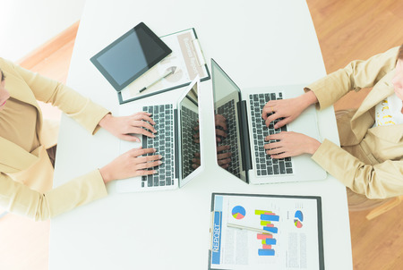 Unrecognizable business person analyzing graphs and taking notesの写真素材