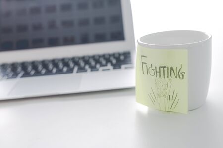 Note and post-it on cup of coffee with laptop