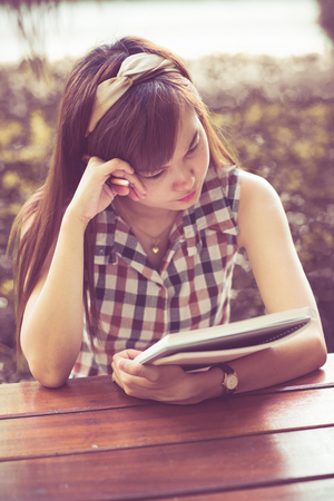 Close-up of a young girl writing into her diary, in the parkの写真素材