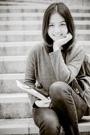 Attractive female college student sitting on stairsの写真素材