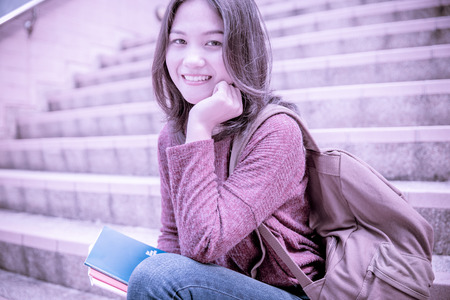 Attractive female college student sitting on stairsの写真素材