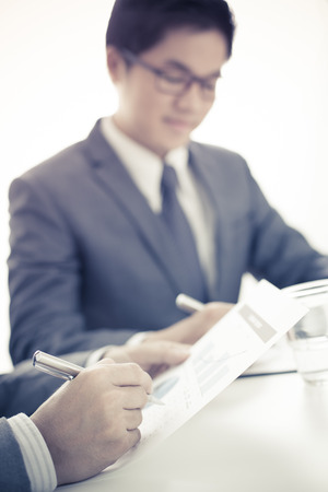 Two businessmen looking at report and having a discussion in office.の写真素材