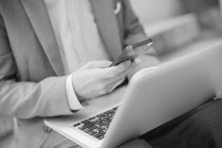 Businessman using laptop pc and mobile phone. He is sitting on a stairs.