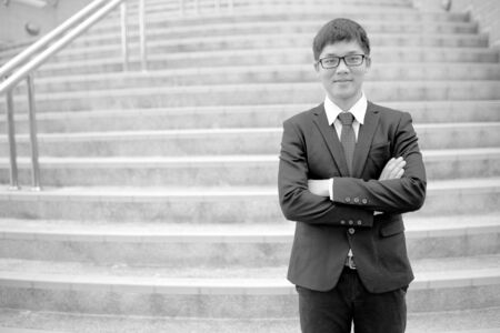 Portrait of a smiling businessman sitting outdoors on stepsの写真素材