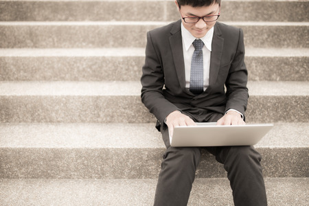 Young man sitting on the stairs using laptopの写真素材