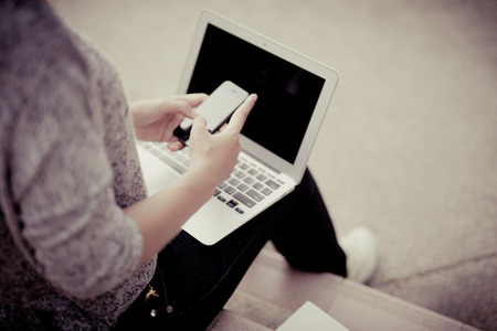 female university student using mobile on stairs