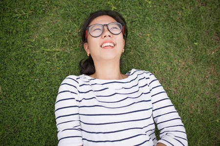 A female college student reading a book while lying on the parkの写真素材