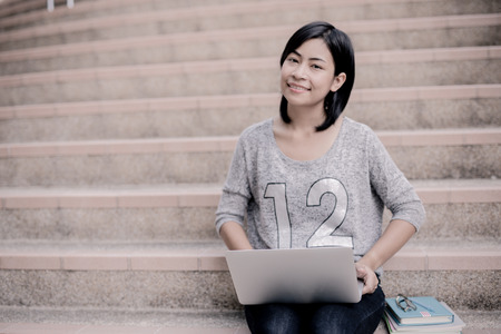 attractive female college student sitting on stairsの写真素材