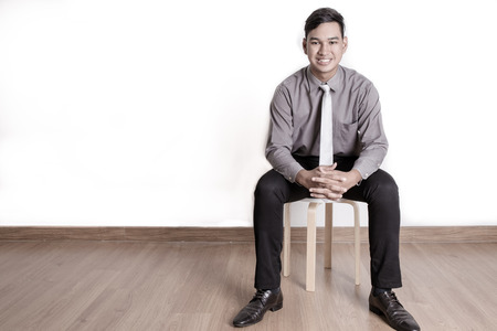 Asian business man sitting on a chair over white backgroundの写真素材