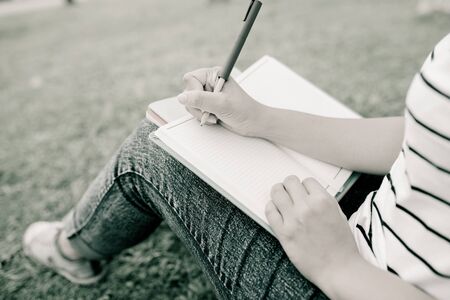 A female college student reading a book while lying on the park